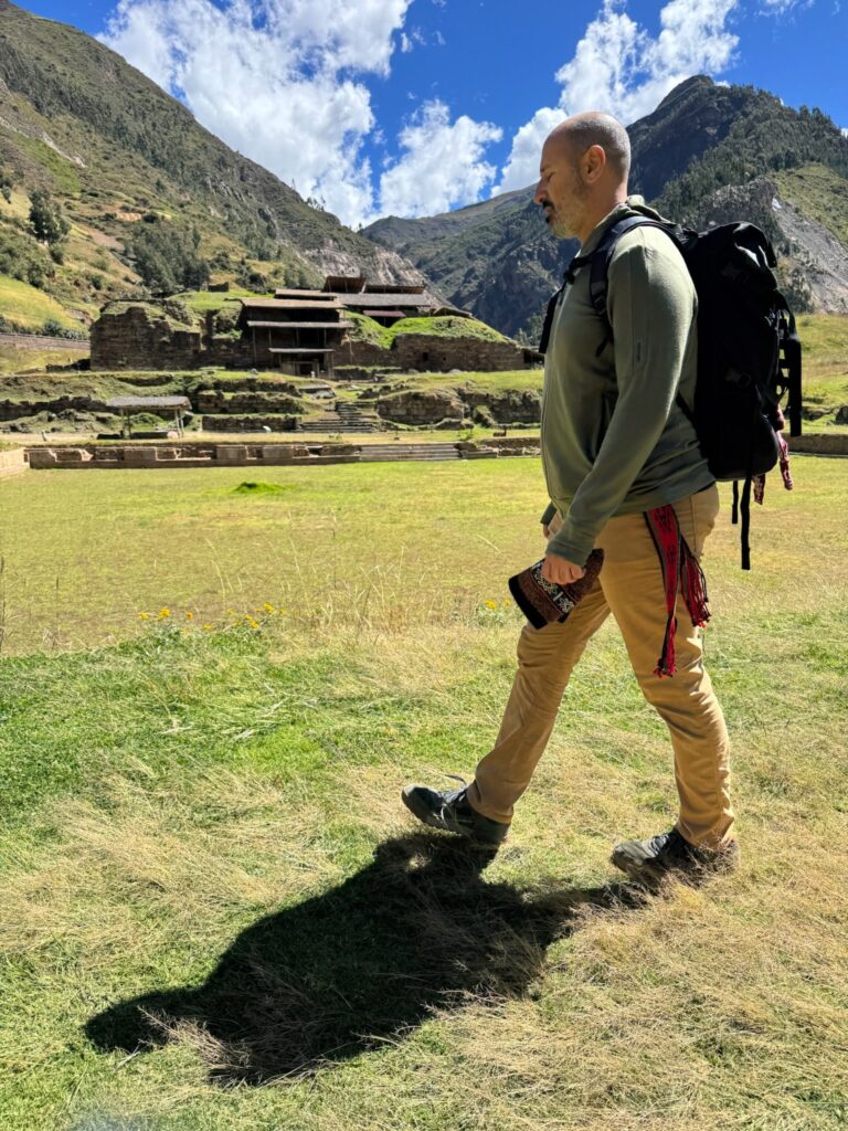 Someone walking across grass below a hillside of stone terraces on a ceremony day