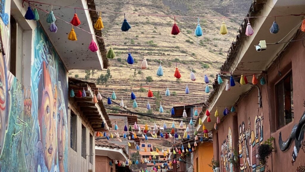 A narrow street in Pisac hung with bunting, its painted walls running towards the mountains